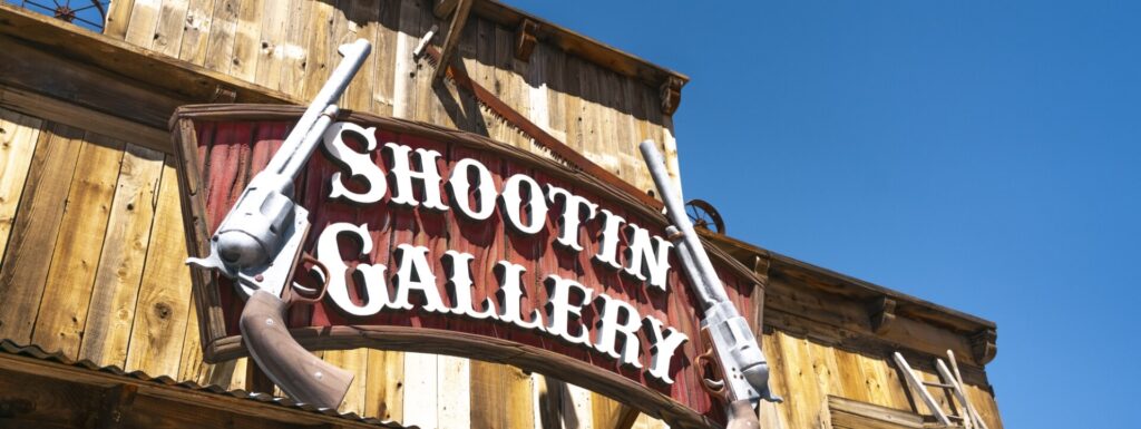 Pointe Hualapai A "Shootin' Gallery" sign with two cowboy revolvers hangs on a wooden building.