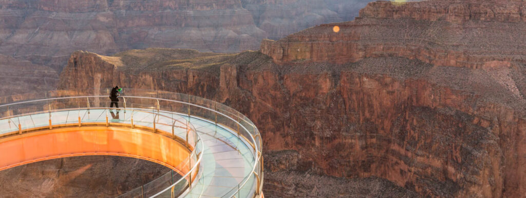 Choses à faire A person stands alone on the Grand Canyon Skywalk, looking out at the canyon.