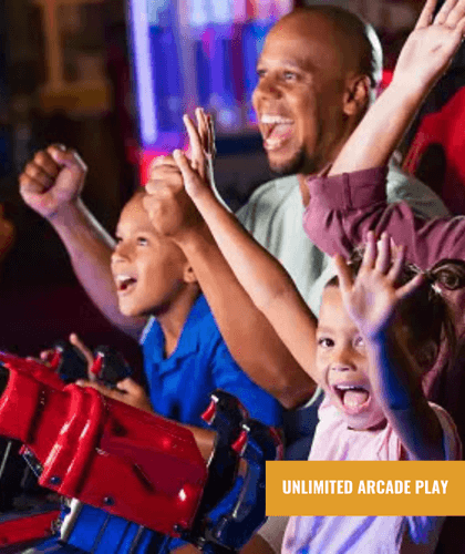 A happy family, two children and an adult, excitedly playing an arcade game.